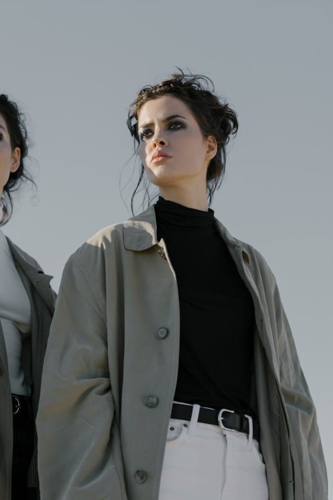 Elegant woman wearing a trench coat poses outdoors, exuding confidence and style.